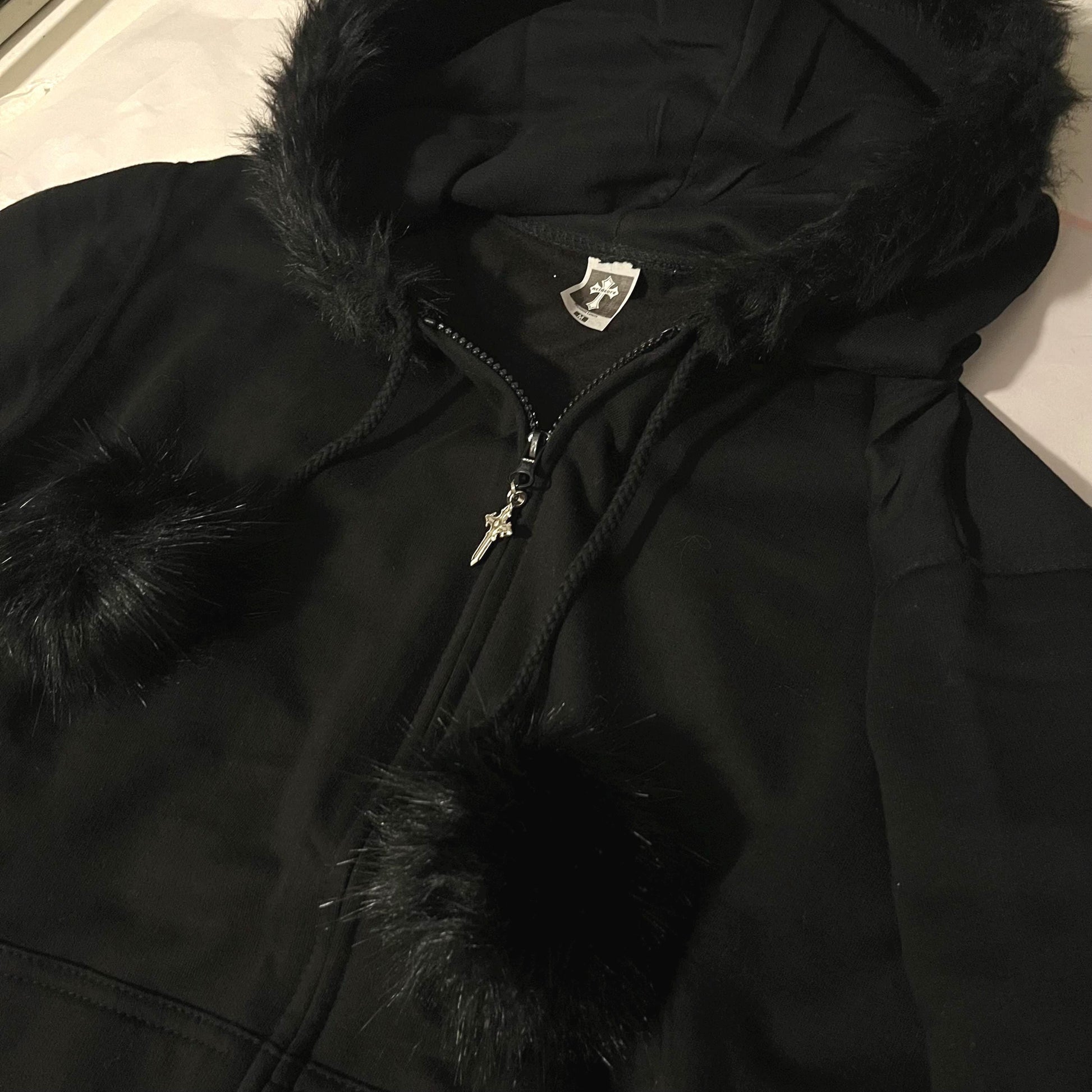 Close Up of pom poms on Black Zip Up Fur Studded Hoodie with Cross Charm